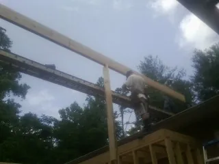 Carpenter setting a ridge beam over a new addition frame — Ice Dam Removal by Roofing Brothers in Ihlen