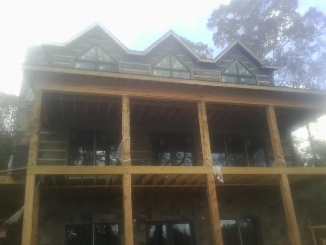 Dormers and porch framing on a large log home under construction — Roof Coating work by our crew in Ihlen