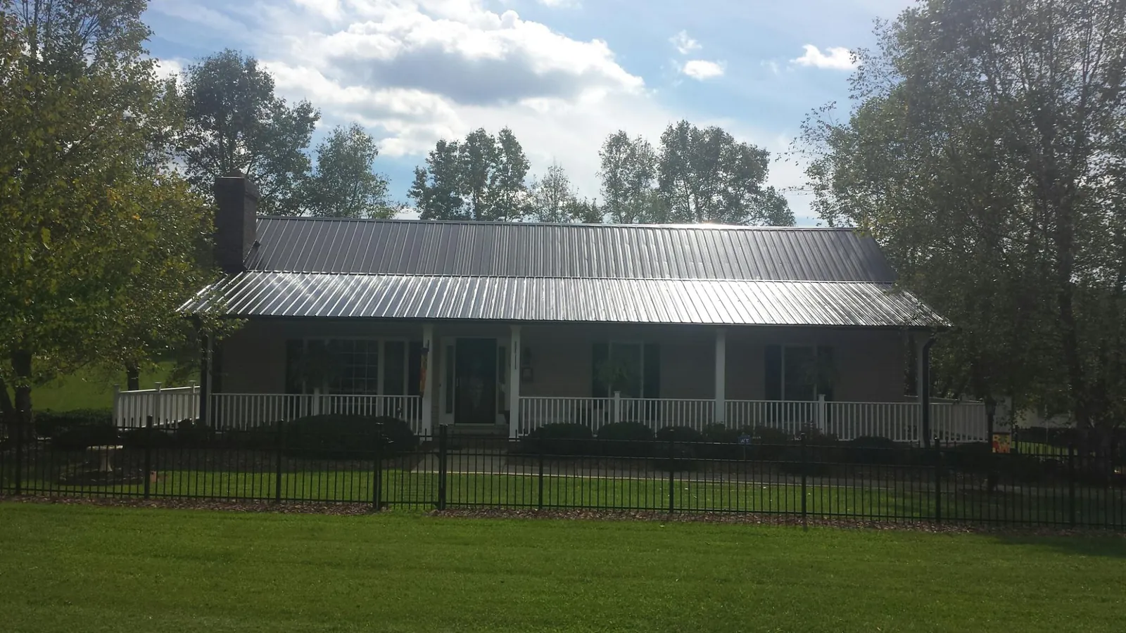 Gray metal roof on a brick ranch with a full width front porch — Gutter Guard Installation work by our crew in Ihlen