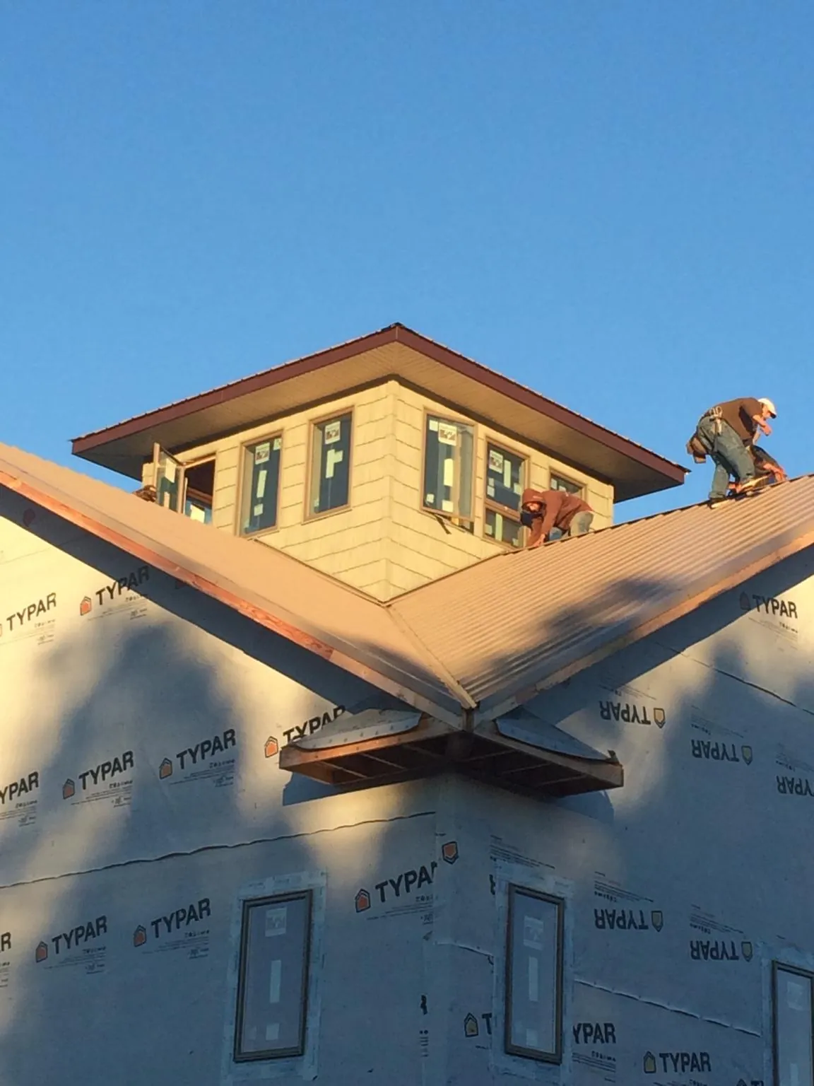 Roofers working around a rooftop cupola on a new metal roof at sunset — Roof Waterproofing in Ihlen by Roofing Brothers